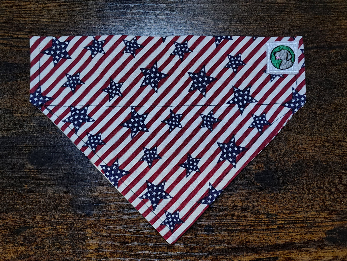 Red, white, and blue striped dog bandanna with star pattern on a wooden surface