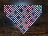 Red, white, and blue striped dog bandanna with star pattern on a wooden surface