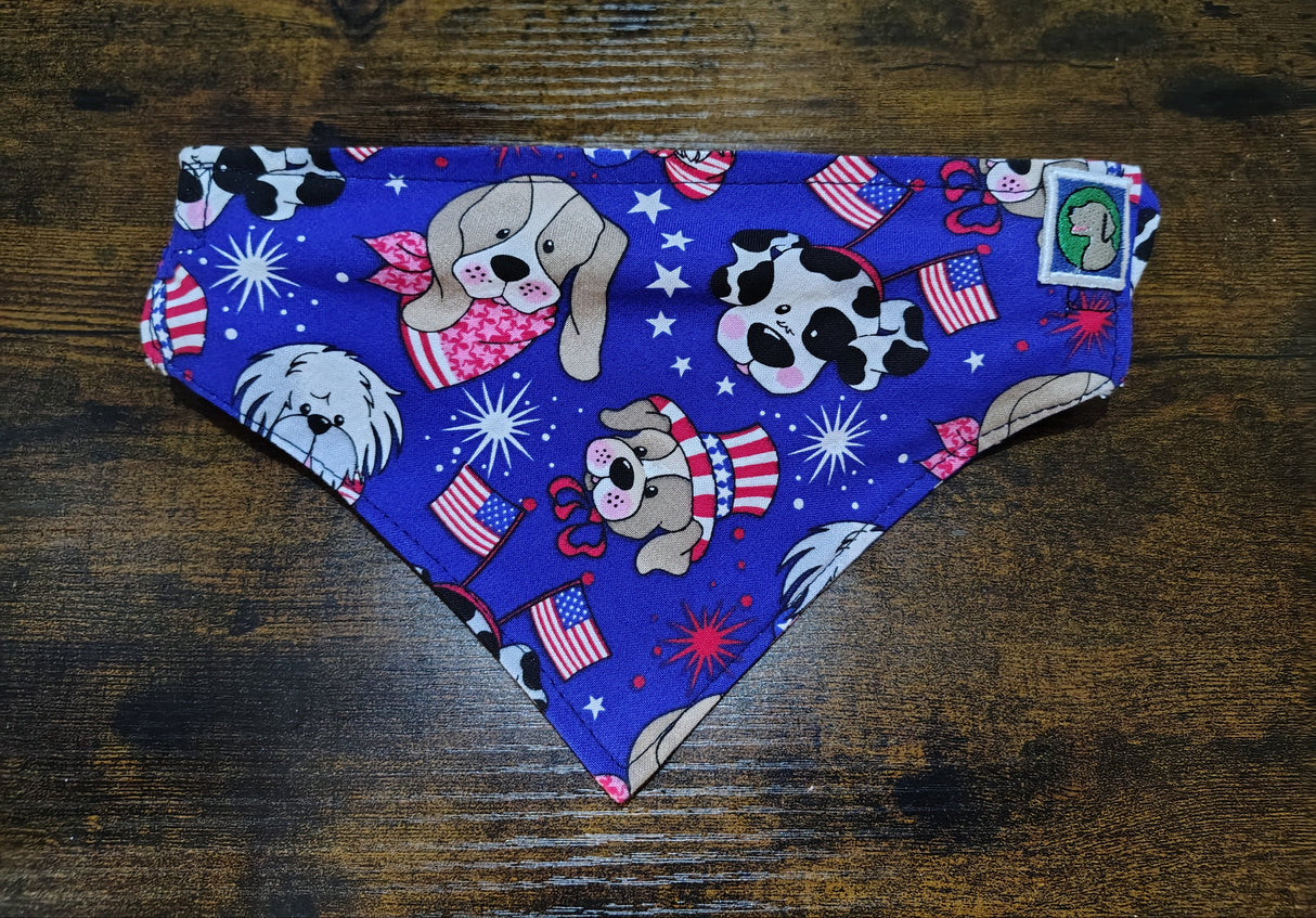 Dog bandana with patriotic design featuring dogs, stars, and flags on a wooden surface