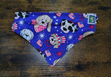 Dog bandana with patriotic design featuring dogs, stars, and flags on a wooden surface
