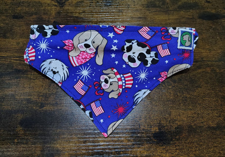 Dog bandana with patriotic design featuring dogs, stars, and flags on a wooden surface