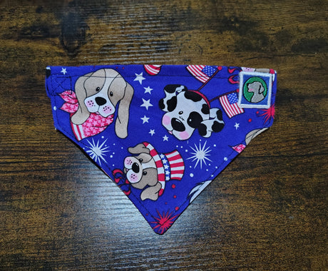 Dog bandana with patriotic design featuring dogs and stars on a wooden surface